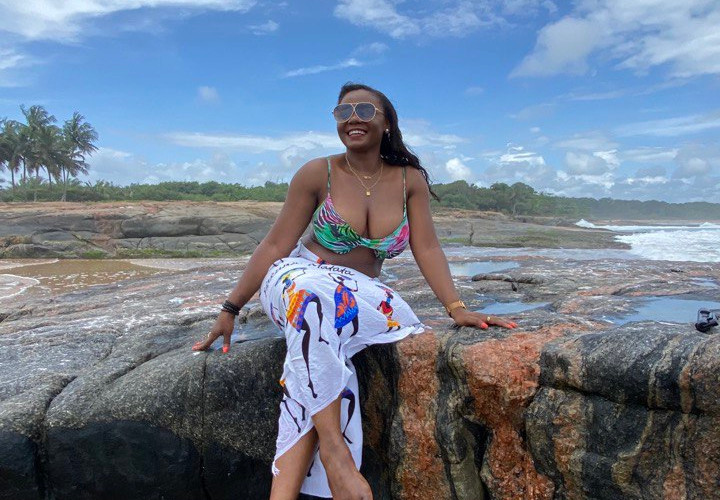 Image of an African beauty sitting leisurely on a rock by the coast of Cote d'Ivoire.Grand Bereby, Ivory Coast