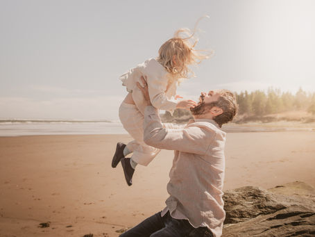 Dad throwing daughter into the air at Rainbow Haven Beach