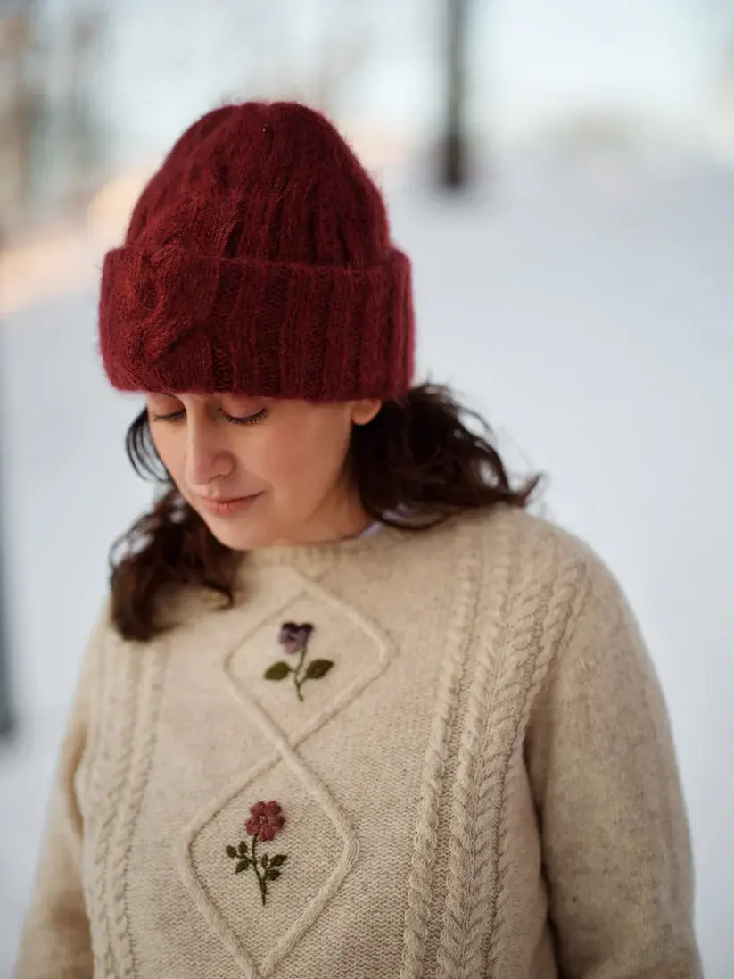 Miniaturbild: Frau mit Strickmütze und Pullover mit Rosenmuster