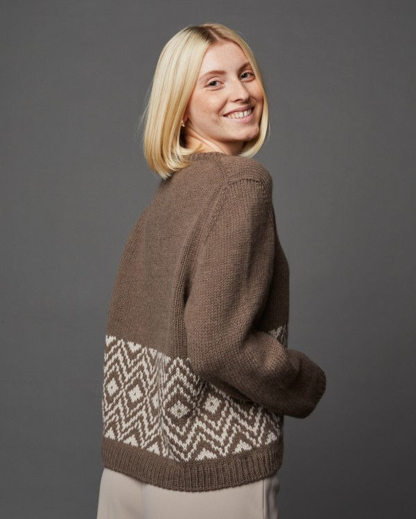 Miniaturbild: Frau in braunem Strickpullover mit geometrischem Muster