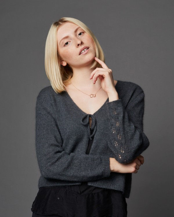 Miniaturbild: Asa, junge Frau mit blonden Haaren, Hand am Kinn, in grauem Pullover