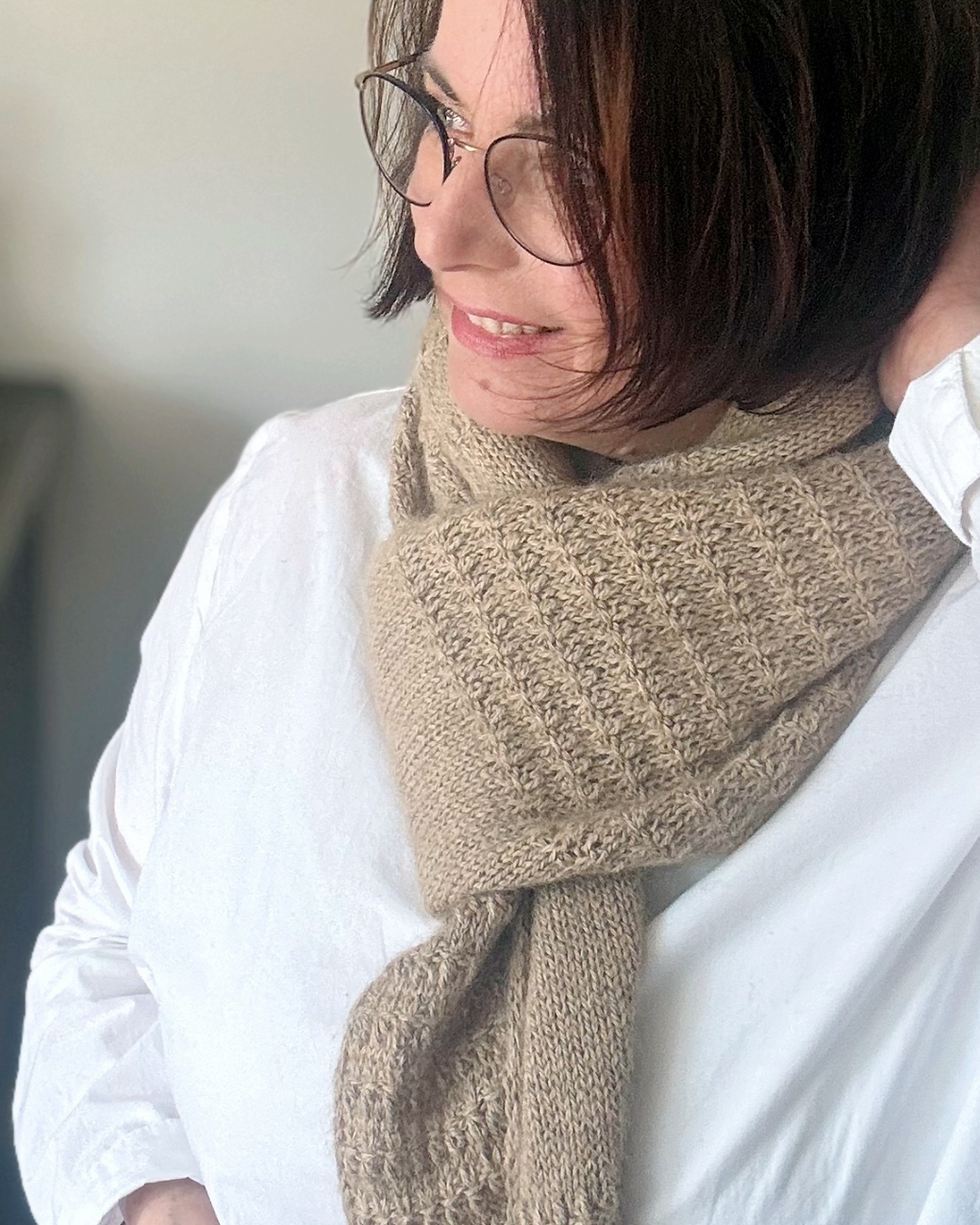 Miniaturbild: Lächelnde Frau mit beigem Strickschal