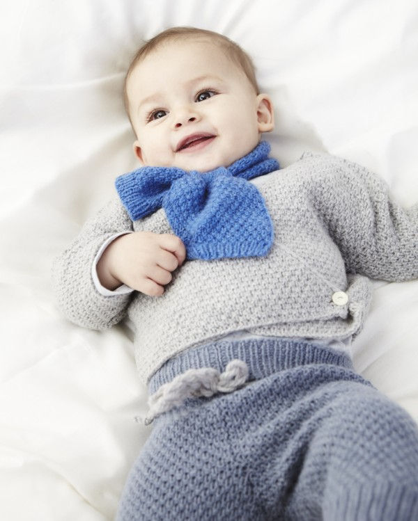 Miniaturbild: Lächelndes Baby in silbergrauem Strickpullover und blauem Schal