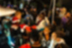 A crowded outdoor scene at the Maryland Leaf party featuring guests wearing Santa hats and reindeer antlers mingling in a festive atmosphere.