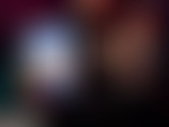 A stylish woman with braided hair and gold jewelry smokes a blunt while holding a District Cannabis Pavé bag against a high-rise city skyline at dusk.