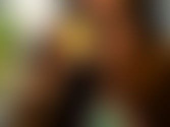 A woman in a brown suit and wide-brim hat holding up a jar of bright yellow Eden solventless rosin toward the camera.