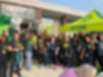 A group of Rise Dispensary employees and community members gathered outside the dispensary entrance under a "Let’s Rise" canopy, celebrating a grand opening with balloons and smiles.