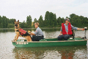 Handler, k9, and boat operator riding a boat.