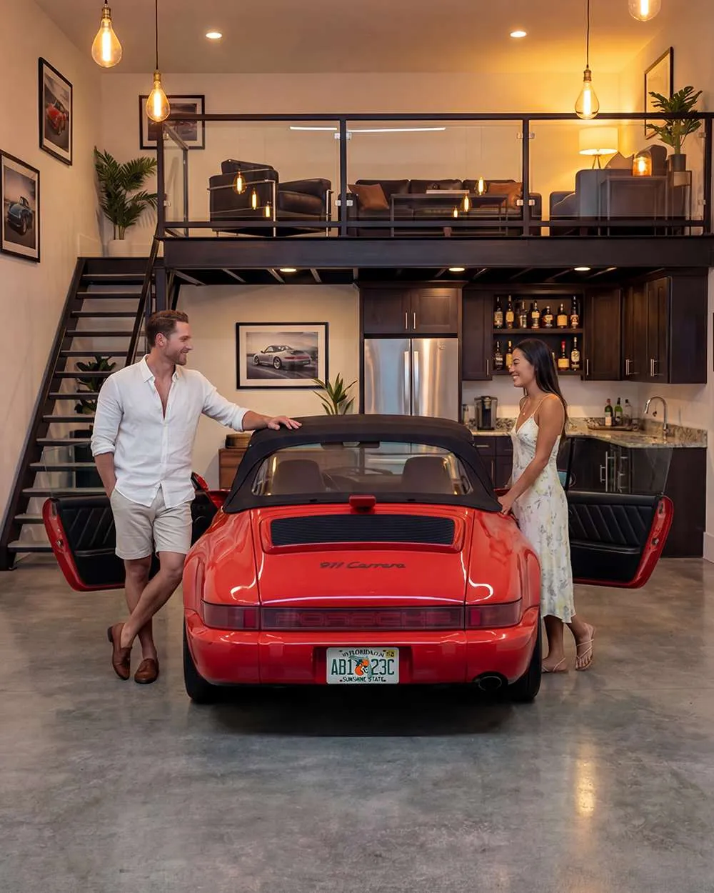 A red sports car is in a garage flanked by a couple, one person on each side. The background shows an office and seating area.