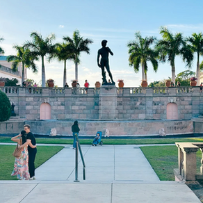 Courtyard with flowers, palm trees, and a large statue.
