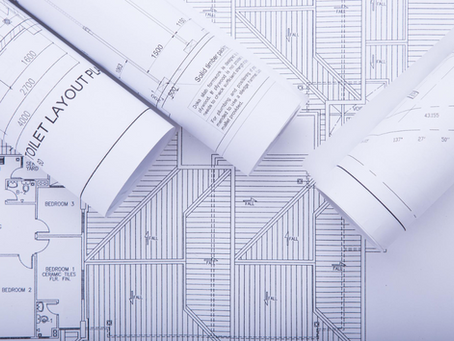 Rolled architectural blueprints on a technical floor plan, symbolizing streamlined permitting with a land use consultant in the Hamptons