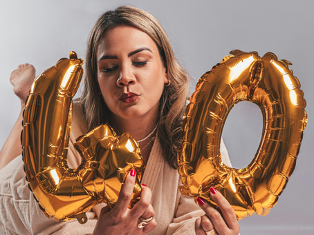 This is an image of a woman holding gold balloons shaped like the number 40, representing perimenopause and menopause awareness for women entering their 40s