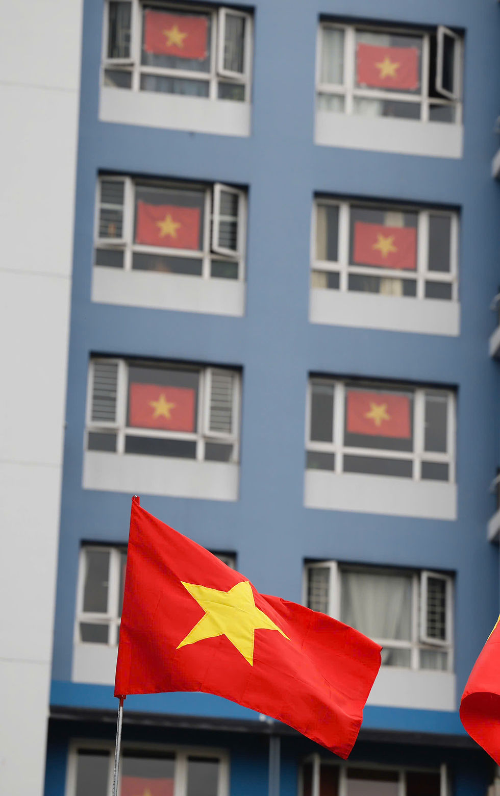 Cờ đỏ sao vàng tung bay. Phía trước Học viện Cán bộ TPHCM, người dân ở một chung cư đã treo cờ Tổ quốc trên nhà, hưởng ứng Đại hội