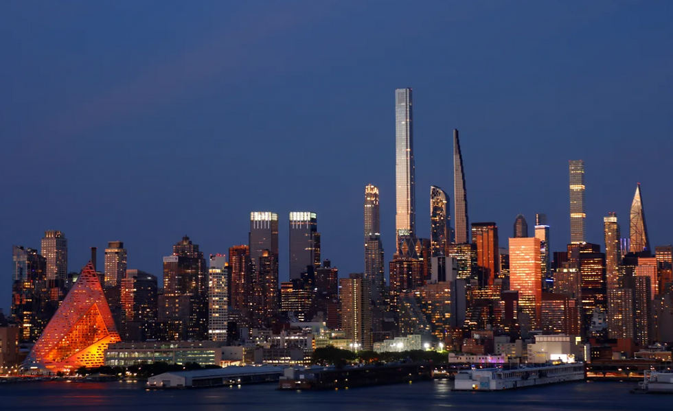 New York City skyline at dusk, featuring illuminated skyscrapers set against a deep blue sky. A triangular building glows orange.
