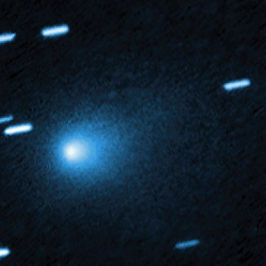Blue comet in dark space, with trails of stars around it, glowing brightly against a black background. No text visible.