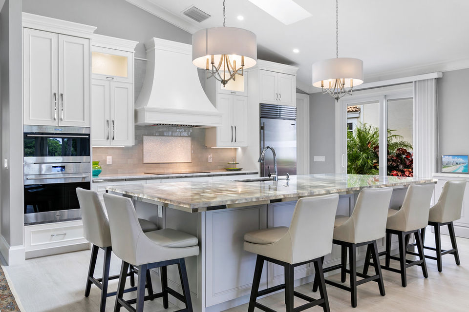 Large white kitchen with marble island and multiple seating areas