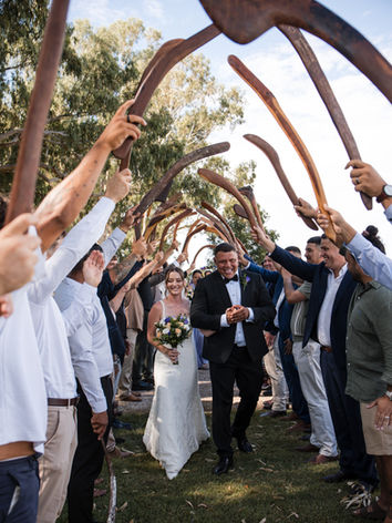 Newly married couple walking through a celebratory guard of honour at Lazy River Estate.