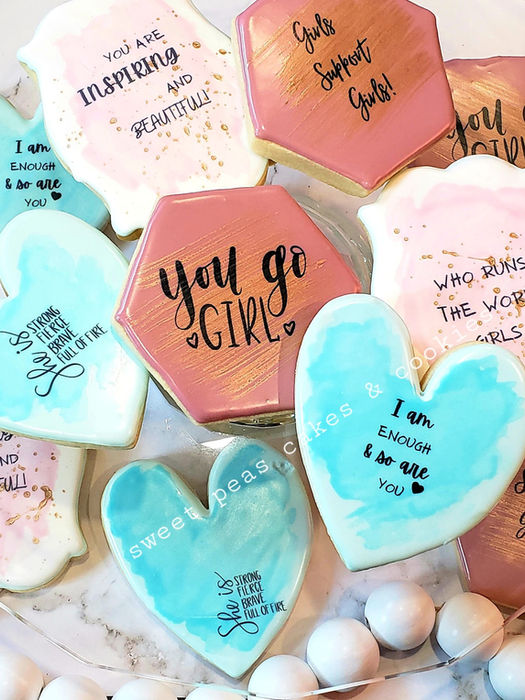 Pastel-colored cookies with hearts, plaques, and hexagons, featuring motivational messages like “You Go Girl,” “God’s Got You Girl,” and “I Am Enough Because He Is.”
