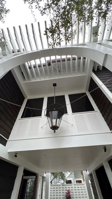 White porch with roof, arched entrance, and a hanging light fixture.