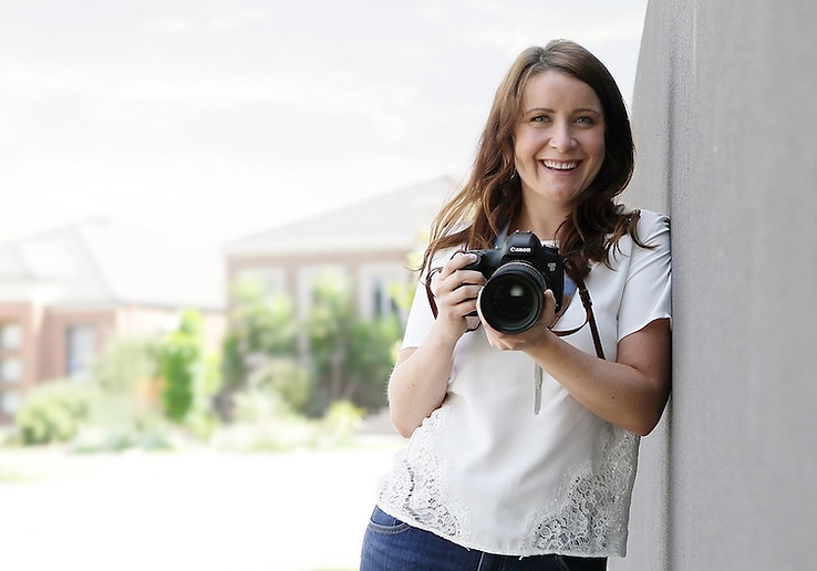Noosa family photographer smiling and holding her camera during an in-home lifestyle portrait session.