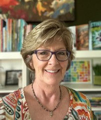 Photo of author Jill Esbaum in front a bookcase.