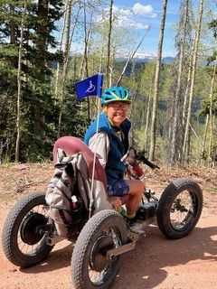 Photo of author Diane Mittler riding her mobility device on a mountain trail/
