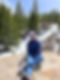 Photo of author Lynn Becker sitting on a rock by a snowy mountain trail.