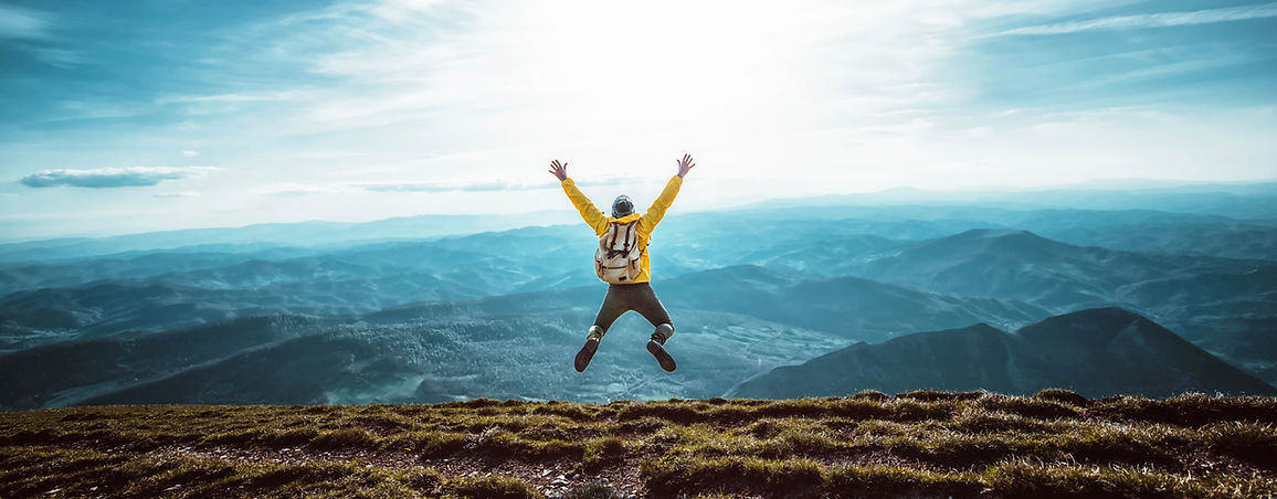 happy-man-with-open-arms-jumping-top-mountain.jpg