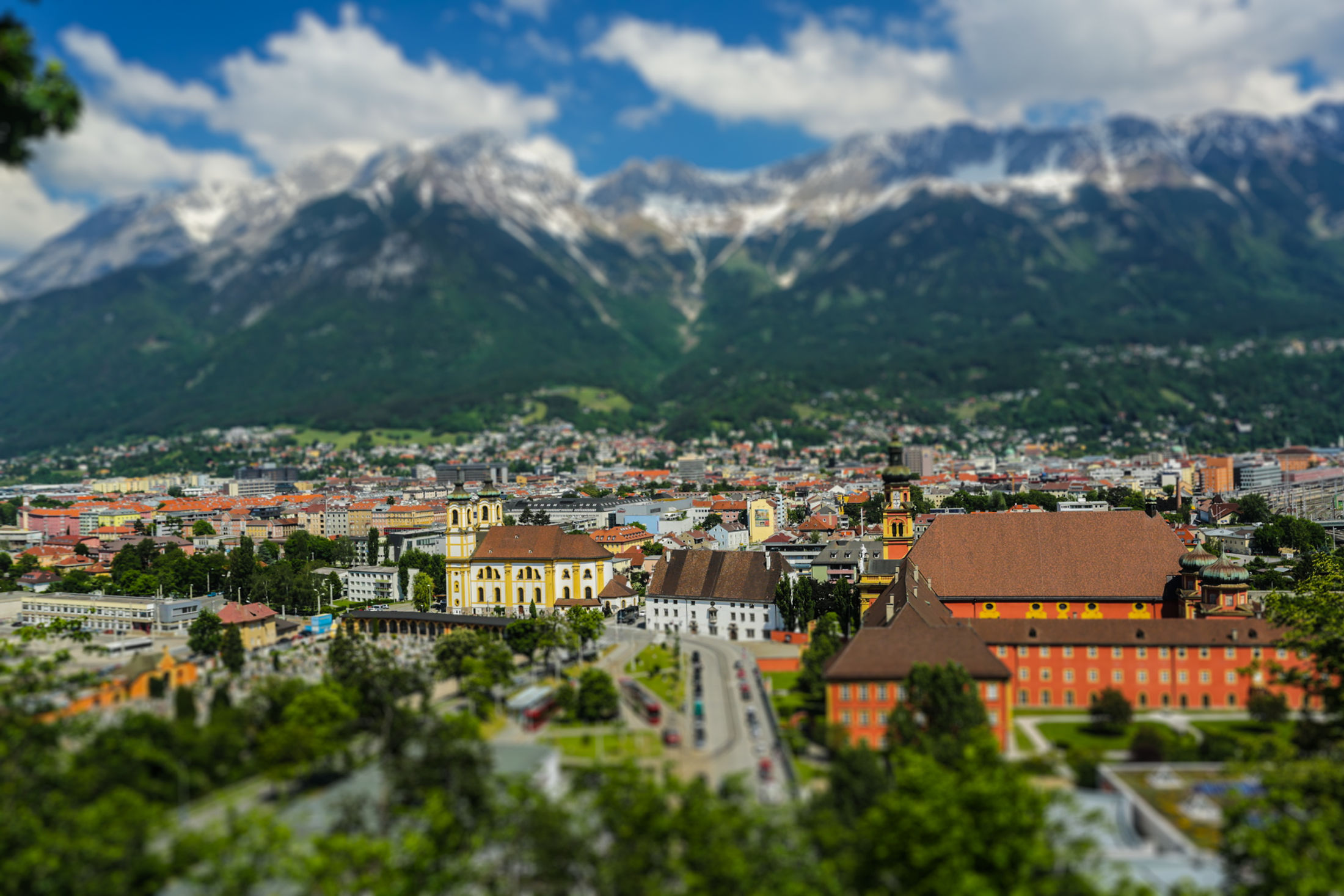 An alpine town beneath rugged mountains and dramatic clouds, travel photograph by Chad Zellmer.