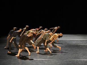 A contemporary dance group strikes a dramatic pose during a captivating performance on stage, showcasing their synchronicity and expressive movements.