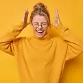 emotional-young-european-woman-exclaims-loudly-keeps-hands-raised-head-keeps-eyes-closed-r