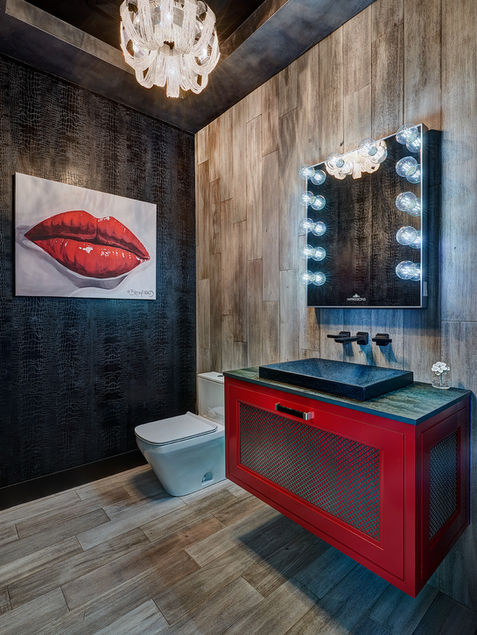 Eclectic powder room with red floating vanity, modern chandelier, and bold lip artwork on black textured wall