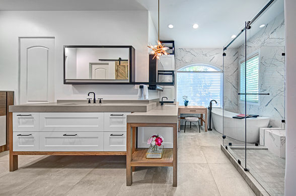 Modern bathroom featuring double vanity with vessel sinks, large mirror, glass shower enclosure, freestanding tub, and marble walls
