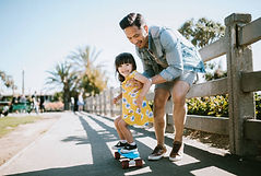 dad teaching little girl skateboard.jpg