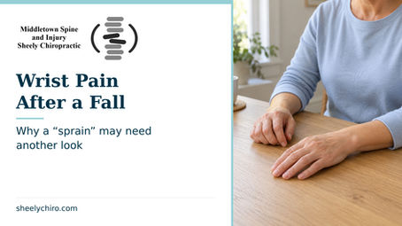 Sheely Chiropractic cover, “Wrist Pain After a Fall.” An adult rests one forearm and both relaxed hands on a table without pressing the wrist.
