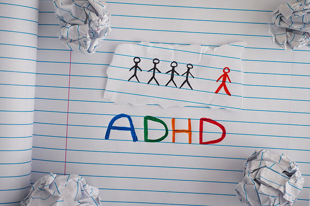 ADHD. Abbreviation ADHD on notebook sheet with some crumpled paper balls on it. Close up.