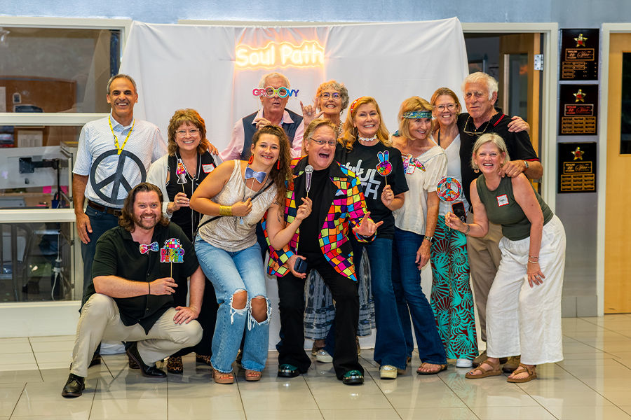 Group photo from The Soul Path Soul Train: Destination 2027 at Taylor Hyundai of Perrysburg, with guests posing in colorful disco-themed attire in front of a glowing Soul Path backdrop.