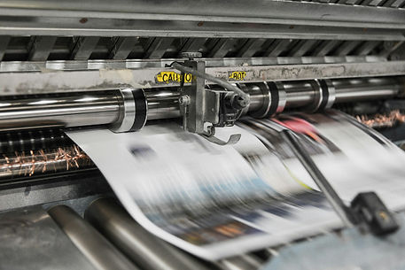 printed sheets of paper moving through a printing press - image by Bank Phrom on Unsplash.