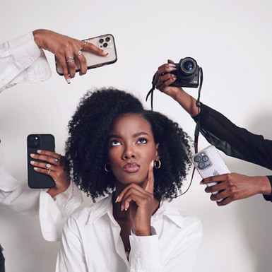 Person surrounded by smartphones and a camera, representing digital media pressure, social influence, and content creation in a minimalist studio setting.