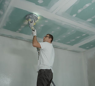 person sanding the drywall that was put up