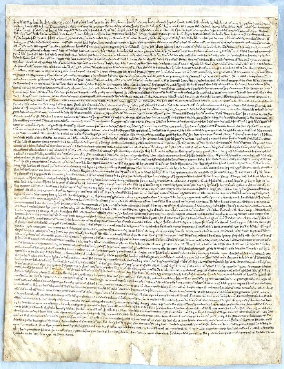 Photograph of an original medieval copy of the Magna Carta written in densely packed Latin script on aged parchment, widely regarded as one of the foundational documents in the development of constitutional law and limits on sovereign power.