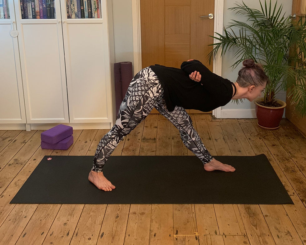 woman on yoga mat with one foot a stride behind the other leaning forward to practice pyramid pose
