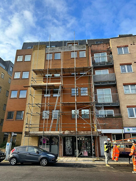 A multi-story building façade under construction, featuring wooden cladding and metal scaffolding