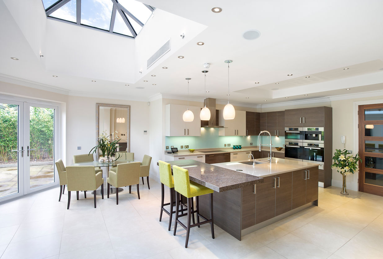 Modern kitchen and dining area with skylight, sleek wood cabinets, island with bar stools, pendant lights