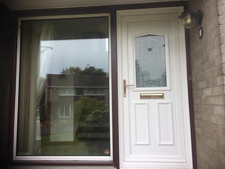 White front door with a gold letterbox and glass panel, next to a large reflective window showing a suburban street