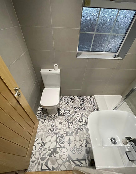 Compact bathroom with tiled walls and geometric-patterned floor