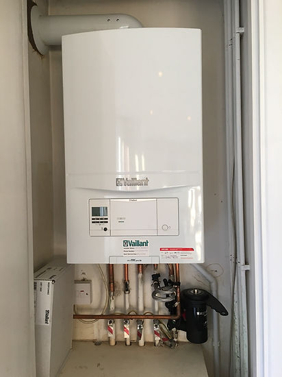 A Vaillant ecoTEC pro 28 boiler is installed on a white wall, with an installer's label attached to it