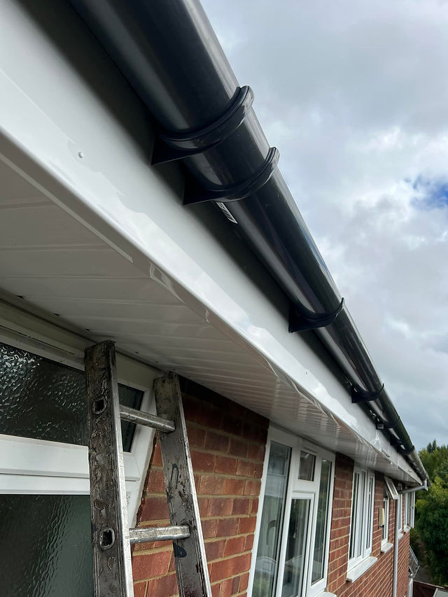Close-up of a clean, white roofline with shiny black guttering