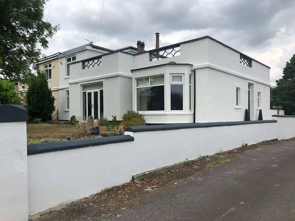 A modern, white stucco house with flat roofs and geometric details is set against a cloudy sky