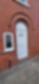 White door with decorative arches and a window on a red brick house